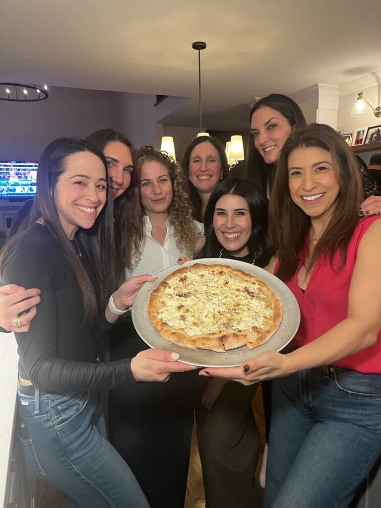 Friends posing with fresh pizza at private chef event